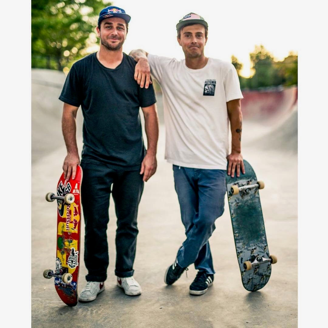 Two mens standing in a skatepark with skateboards