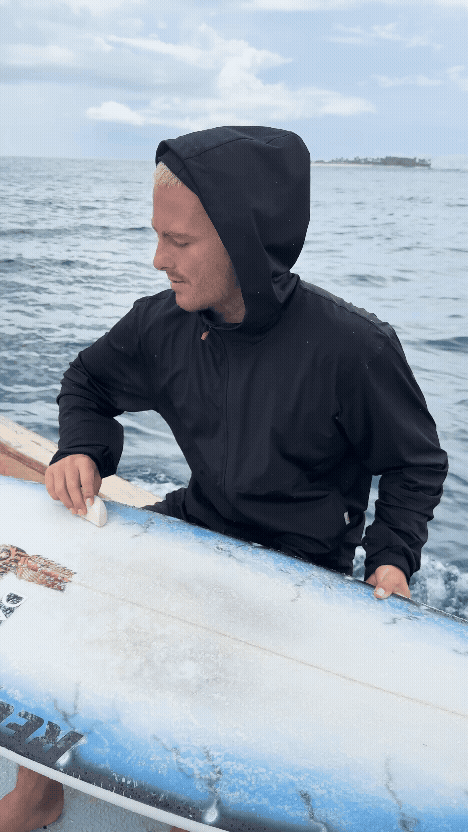 GIF of a man waxing his surfboard