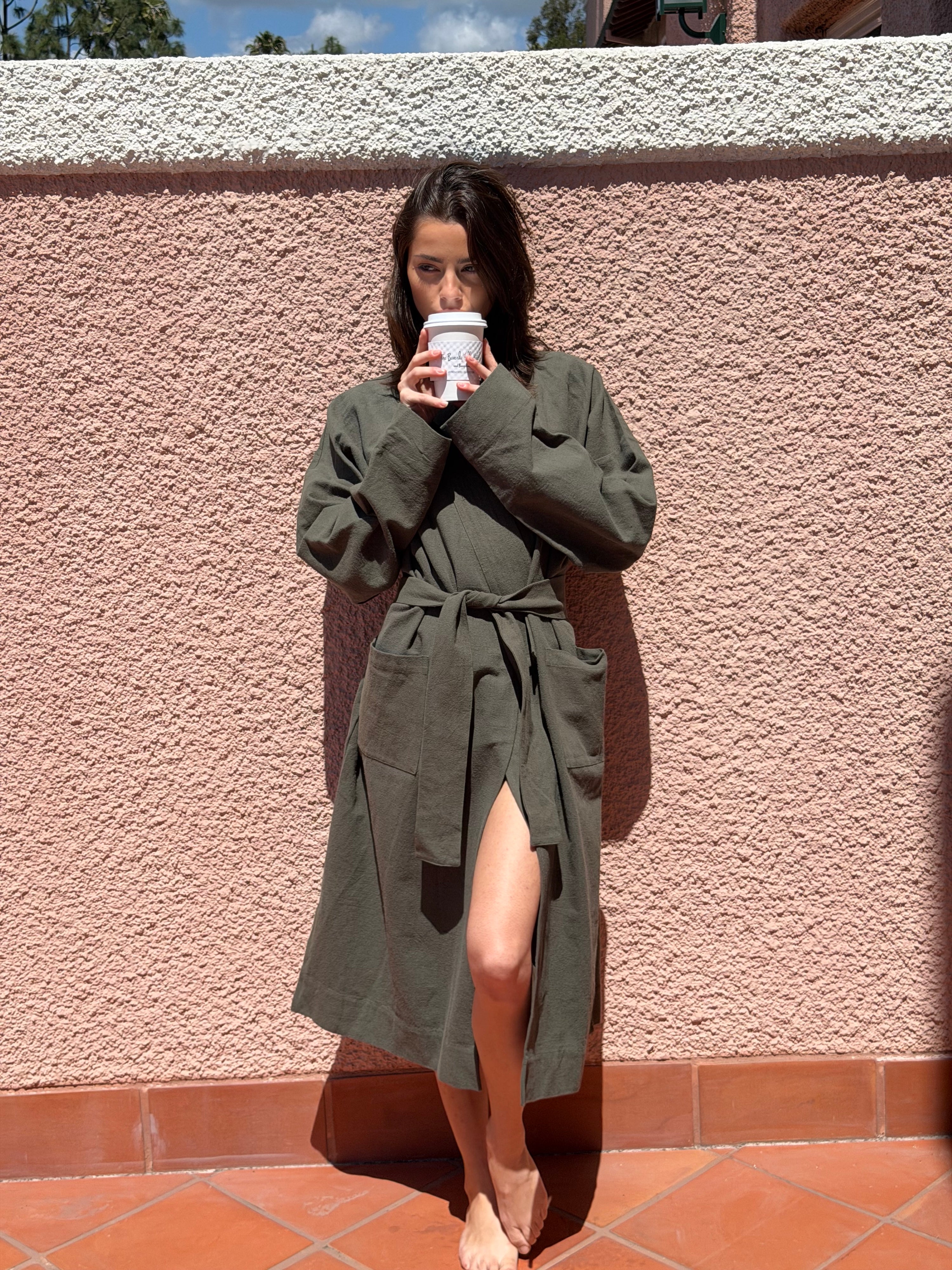 Woman leaning against a wall wearing a green robe