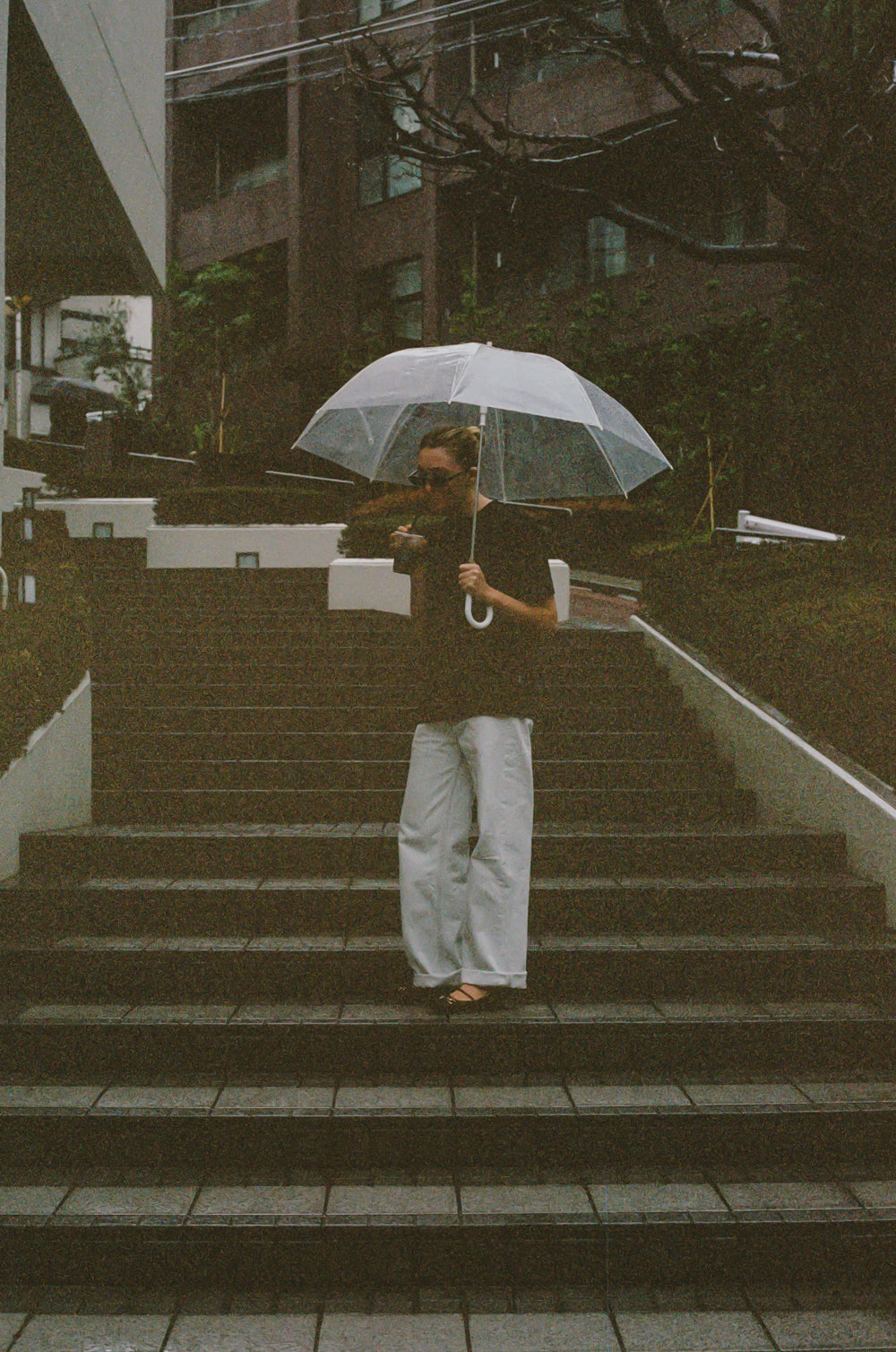 Person holding a transparent umbrella on a set of stairs with a blurred background