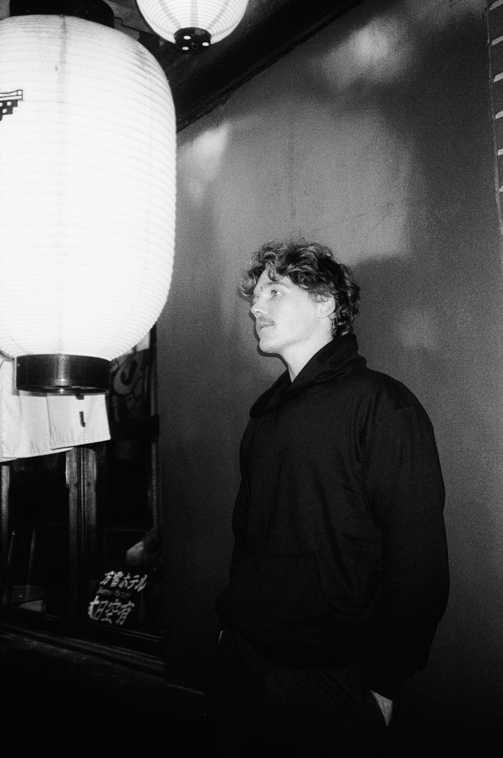 Person standing in a room with a large light fixture and a textured wall.