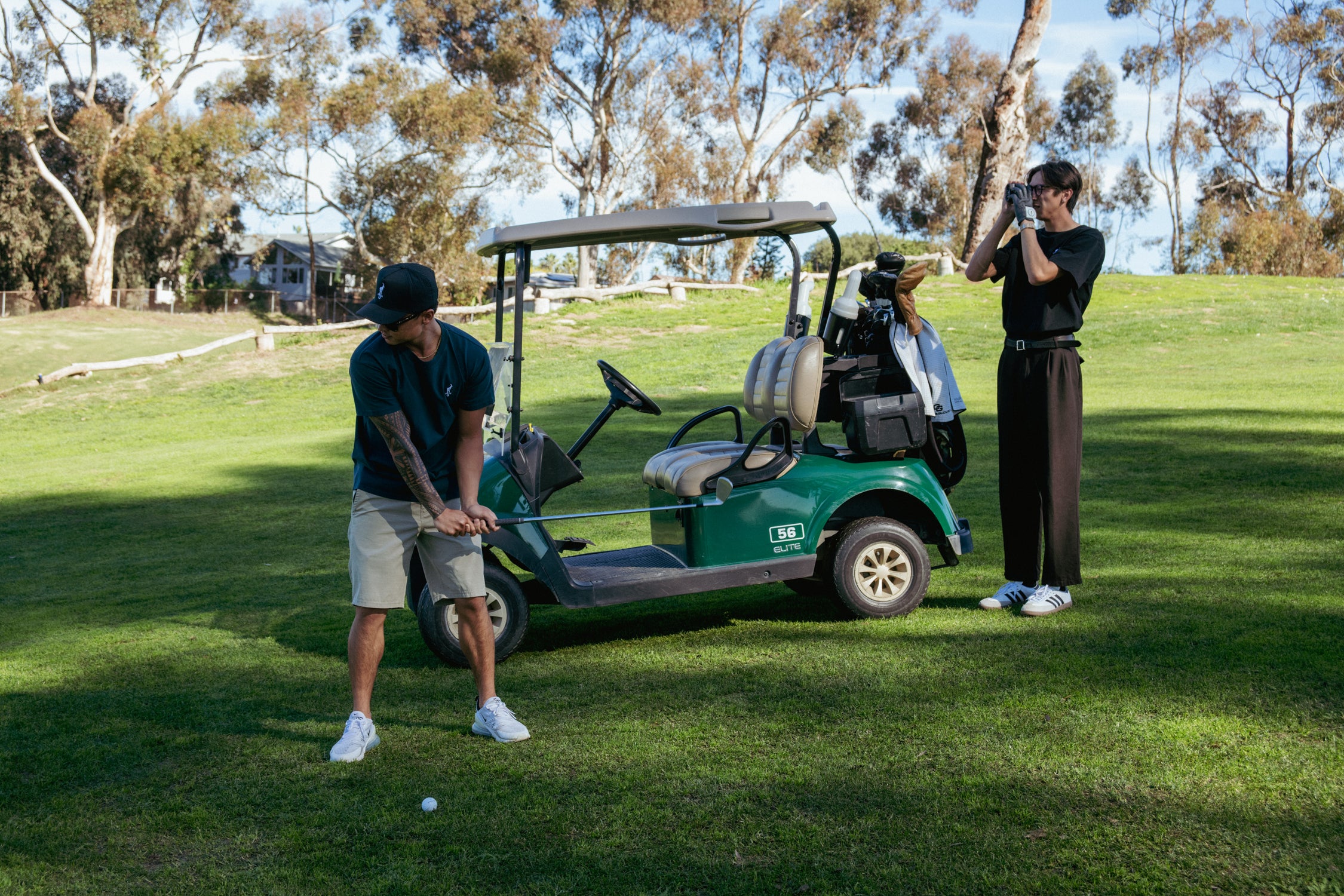 Two people on a golf course with a golf cart in the background