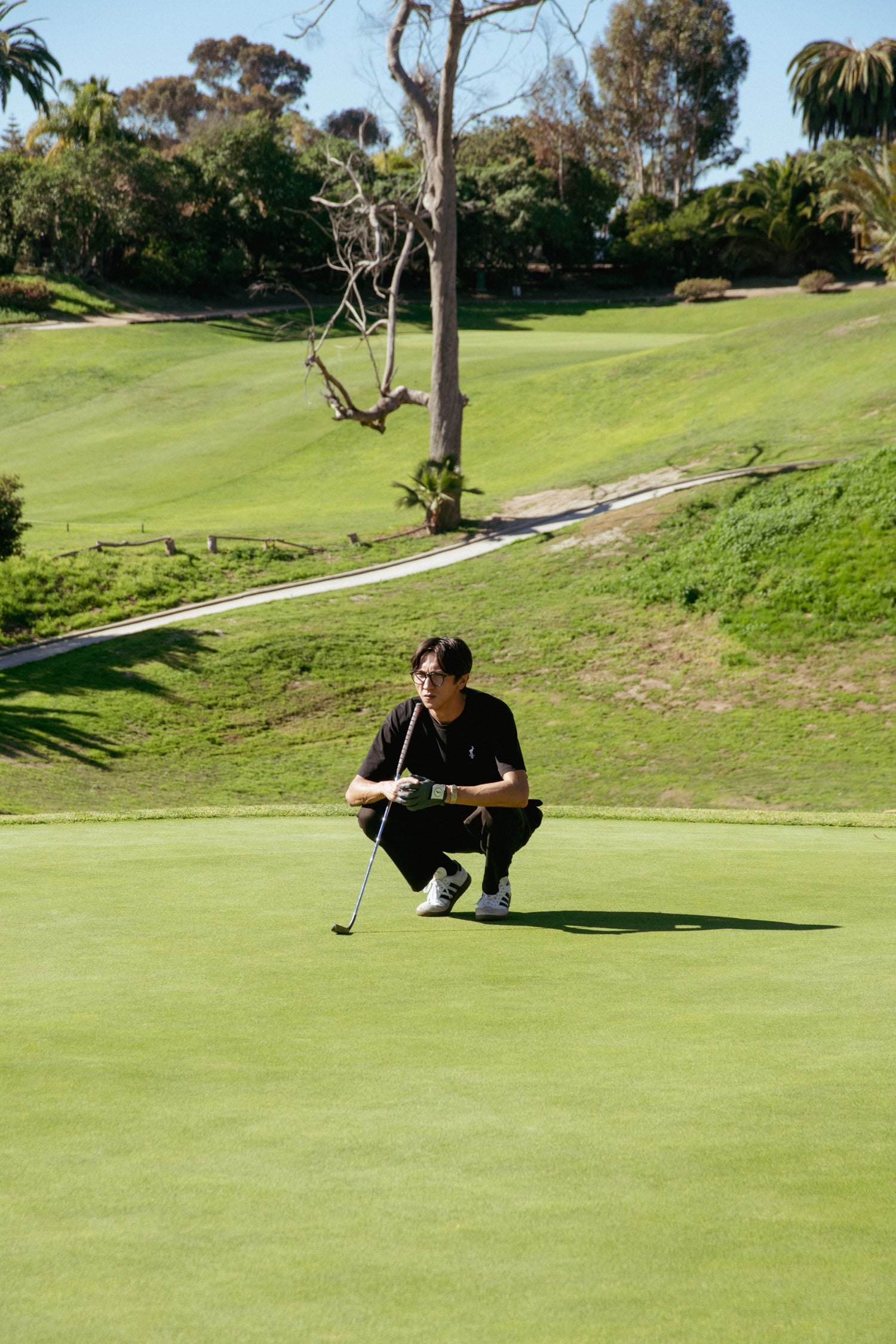 Person on a golf course preparing to putt with a golf club.