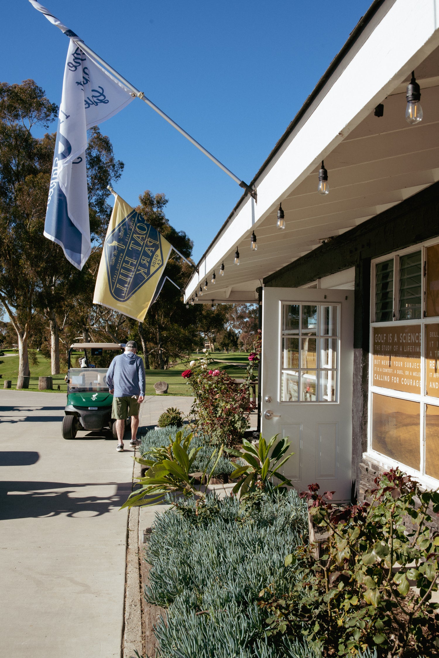 Golf cart and person near a building with flags on a clear day