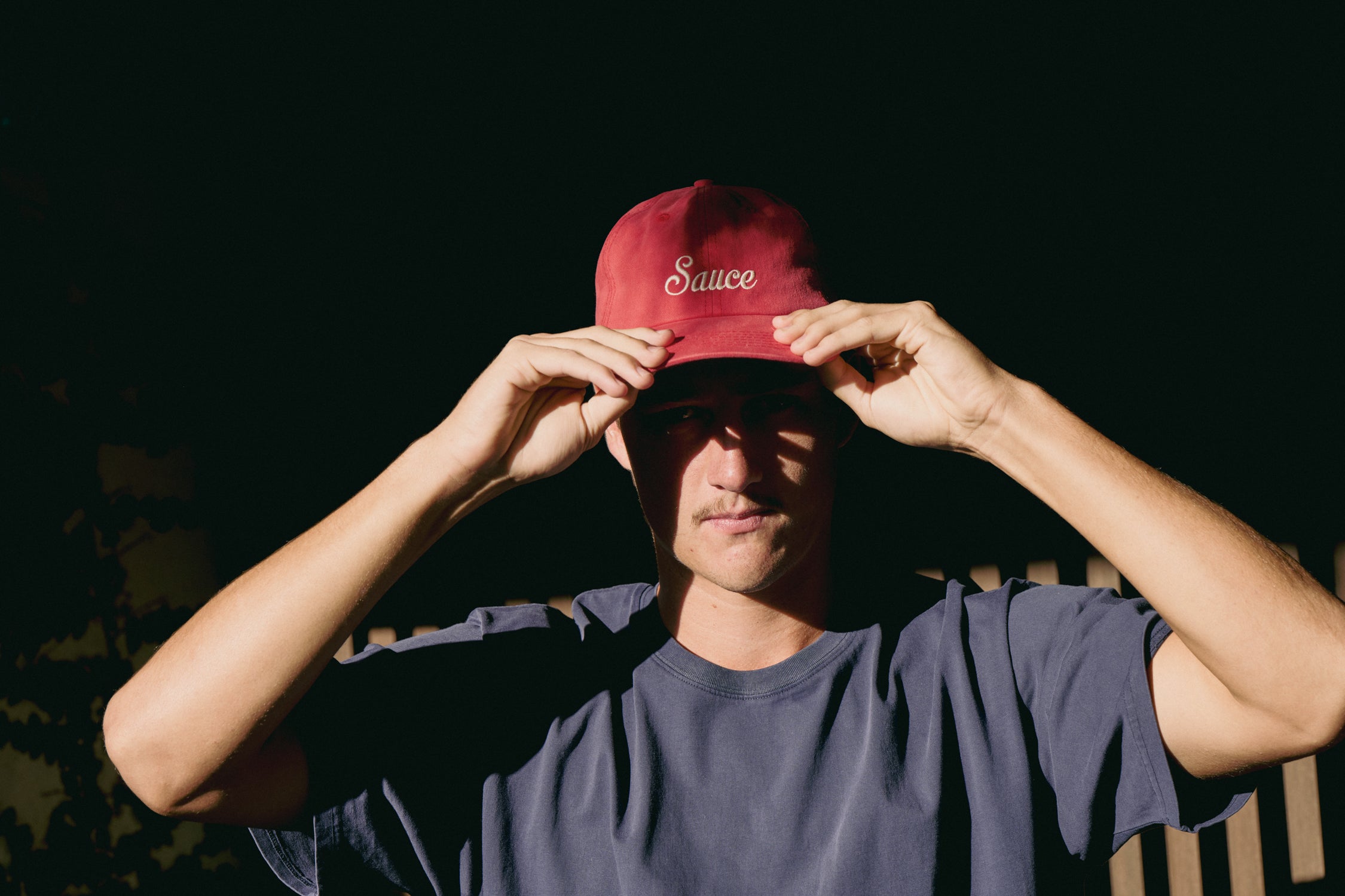 Person wearing a red cap with 'Sauce' text against a dark background