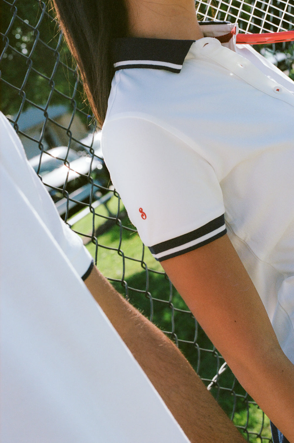 Person wearing a white outfit with black trim on a tennis court