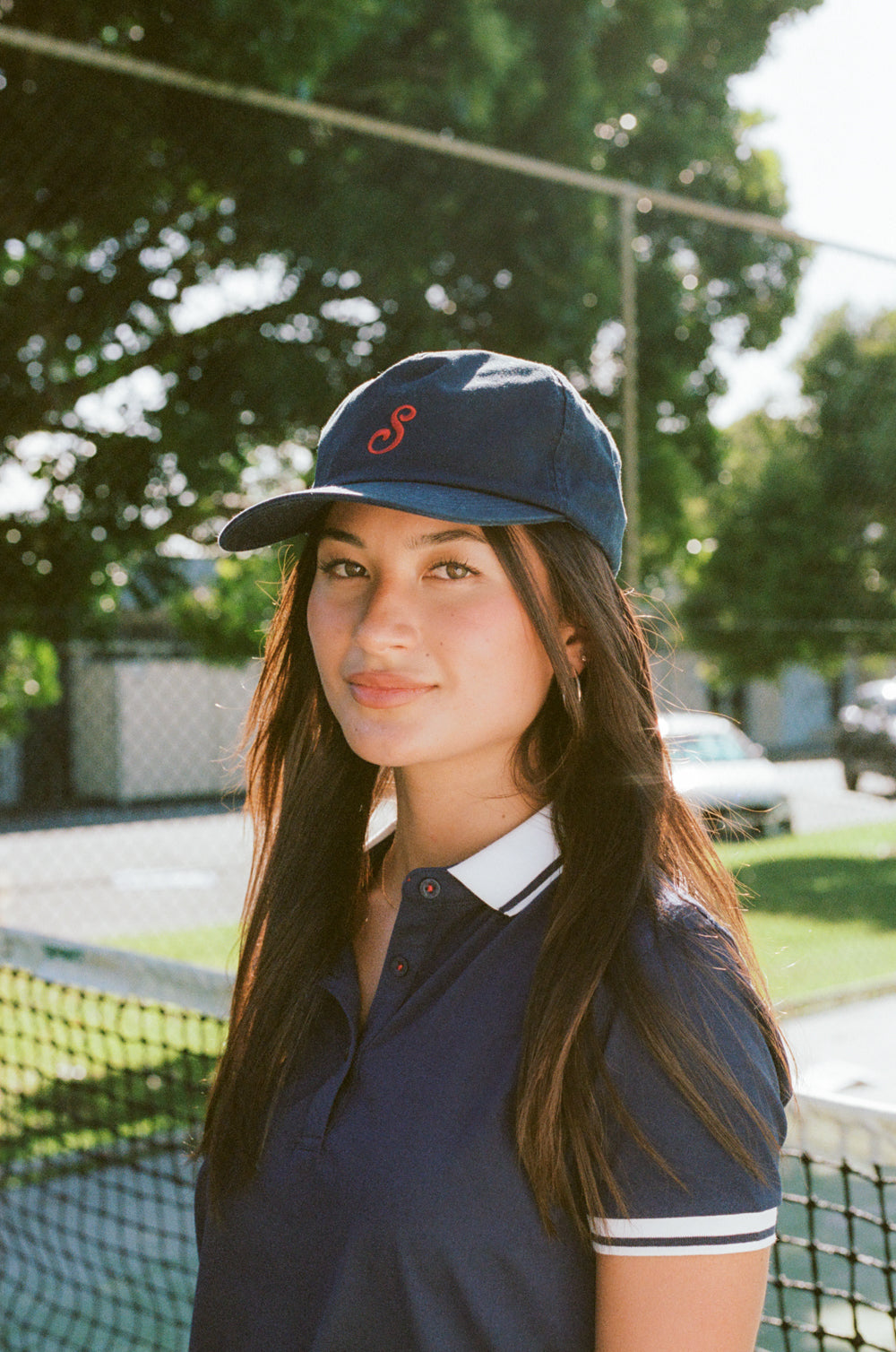 Woman wearing a navy cap and polo shirt on a tennis court