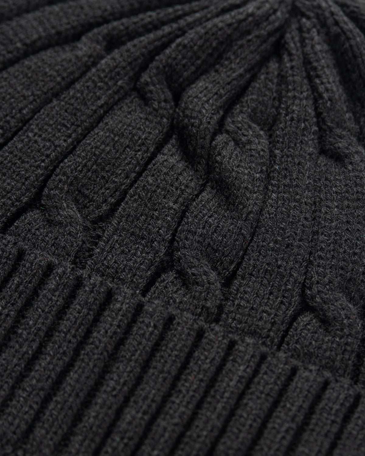 Close-up of a dark gray knitted cable-patterned beanie