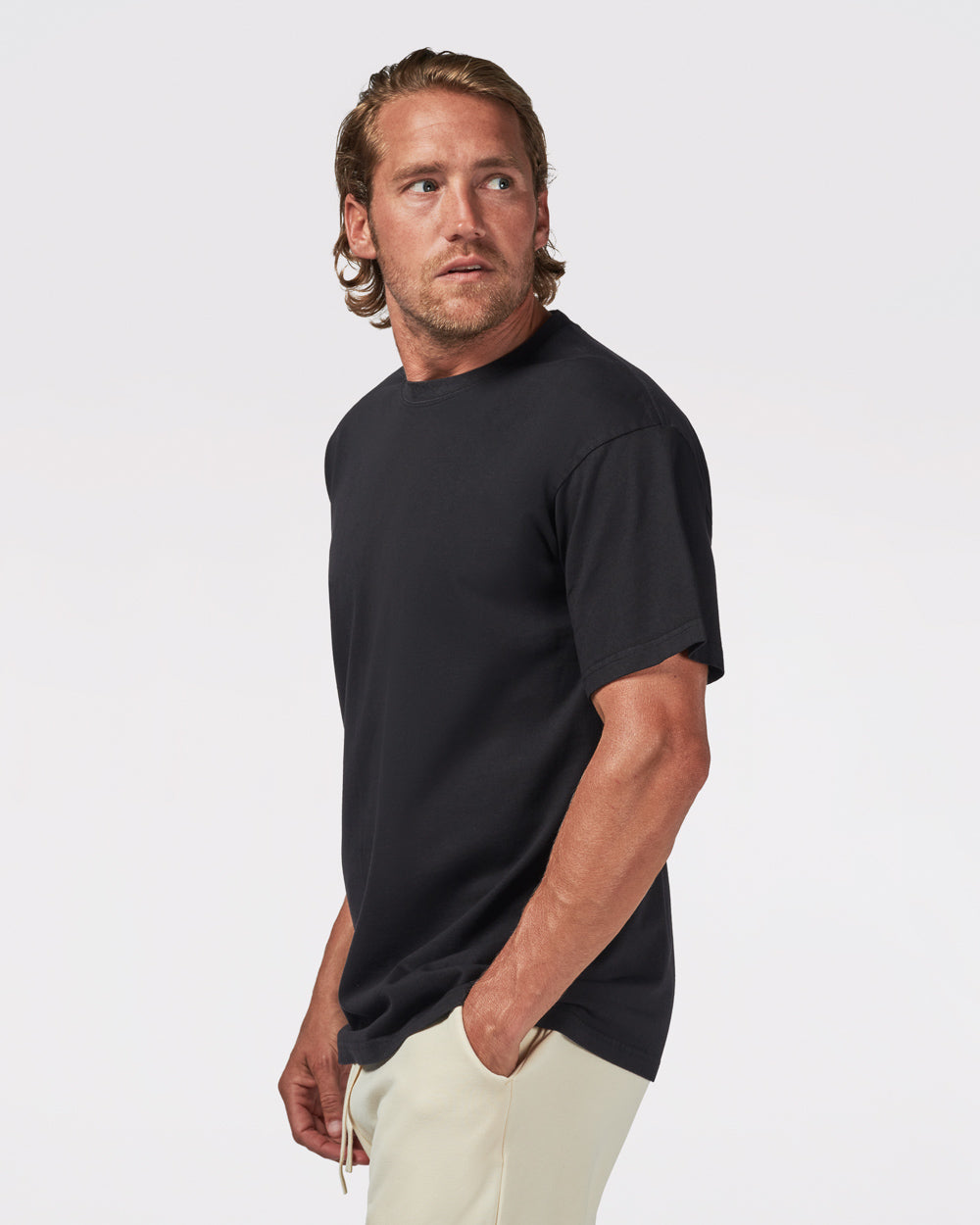 A male model wearing a black garment-dyed t-shirt and beige pants.