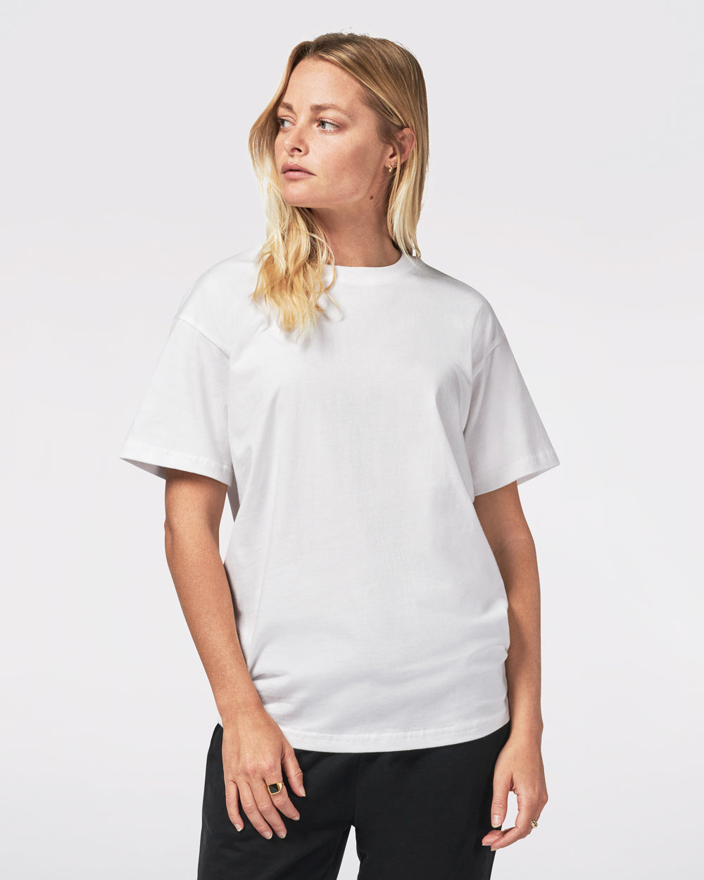 A person wearing a white garment-dyed t-shirt and black pants, posing against a neutral background.