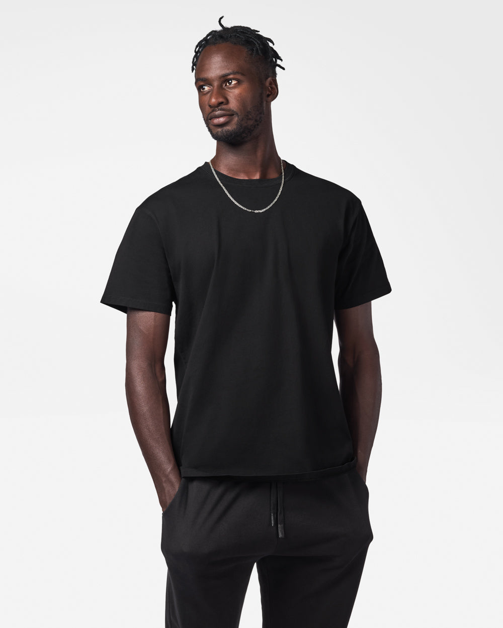 Man wearing black sweat pants and a black t-shirt on a white studio background