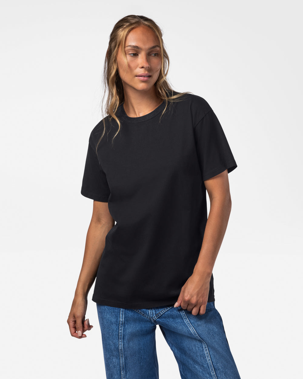 Woman wearing wearing a black t-shirt and jeans on a white studio background