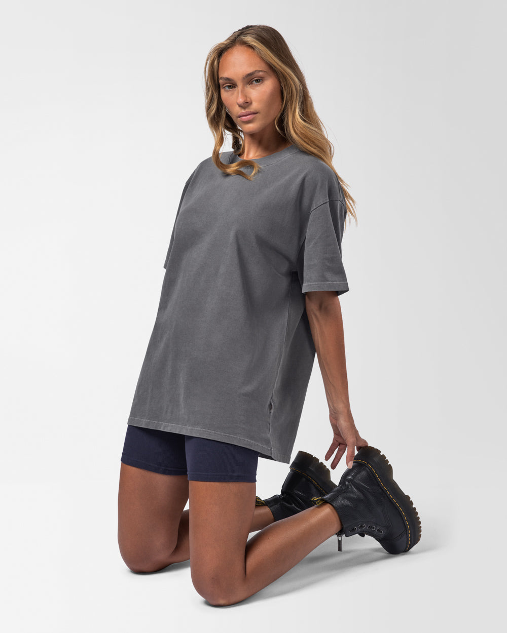 Female model wearing a dark grey t-shirt and black boots on a white background