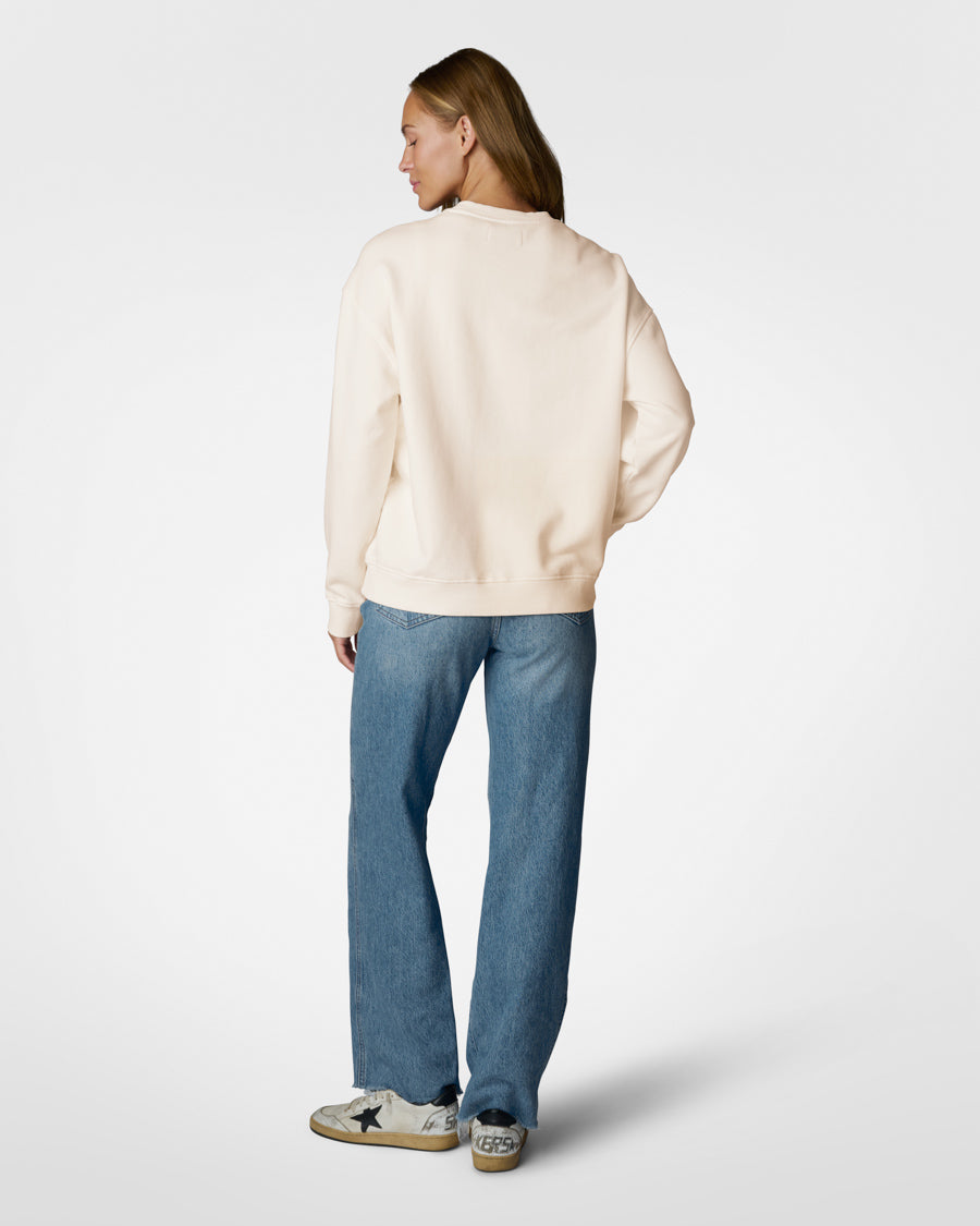 Person wearing a beige sweater and blue jeans on a white background