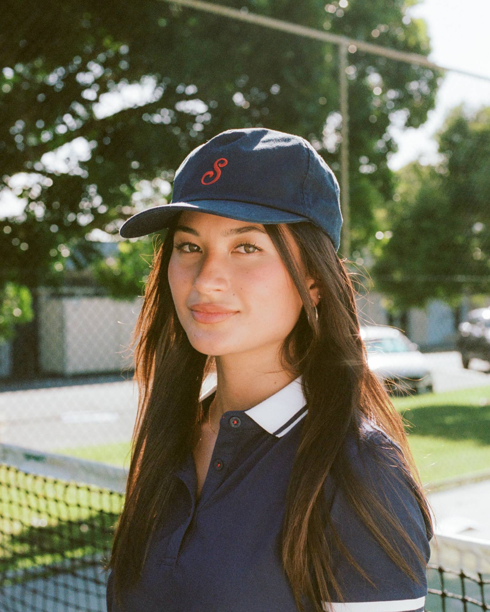 Woman wearing a navy cap and shirt on a tennis court