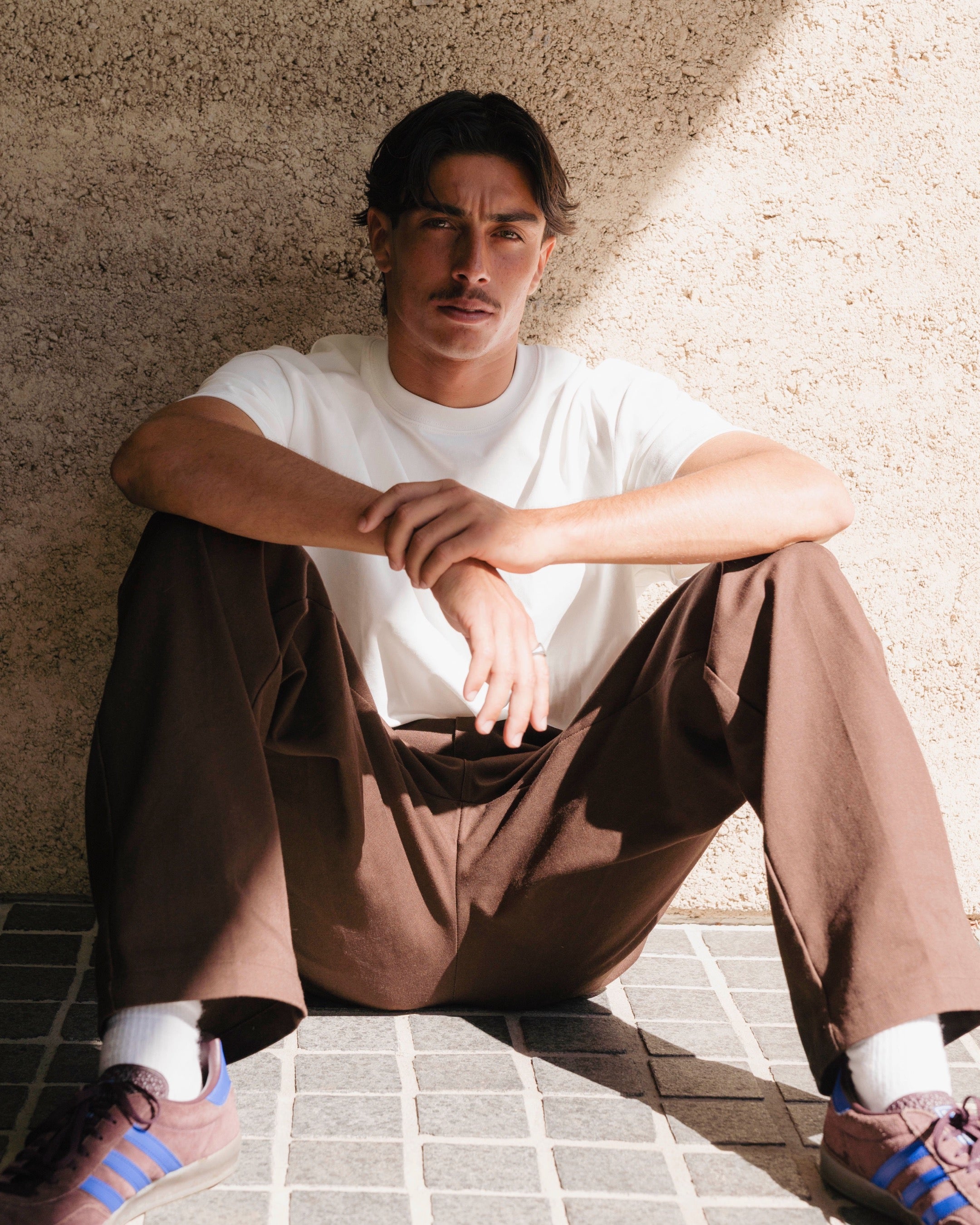 Person sitting on a tiled floor against a textured wall