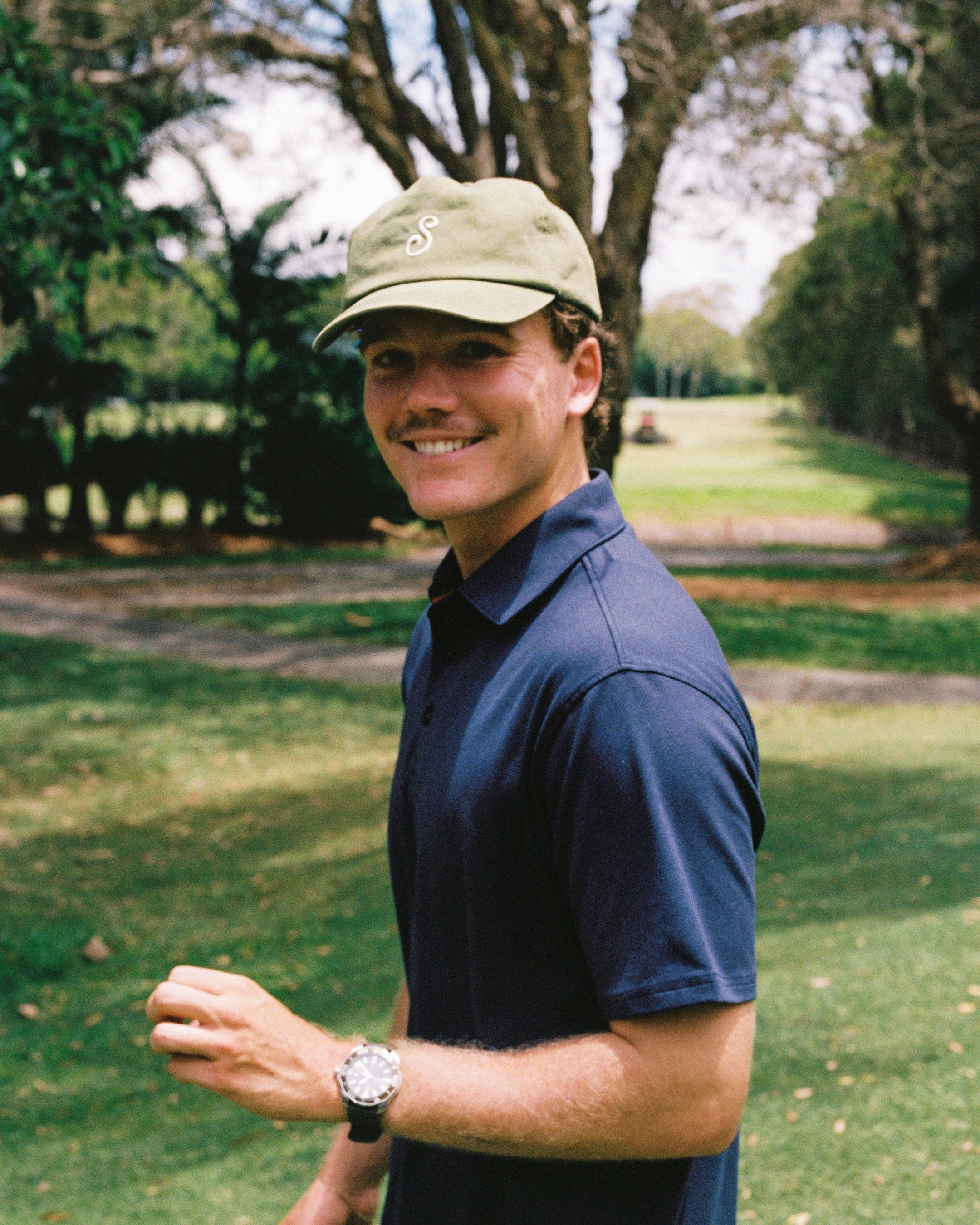 Man wearing a cap and blue shirt in a park setting