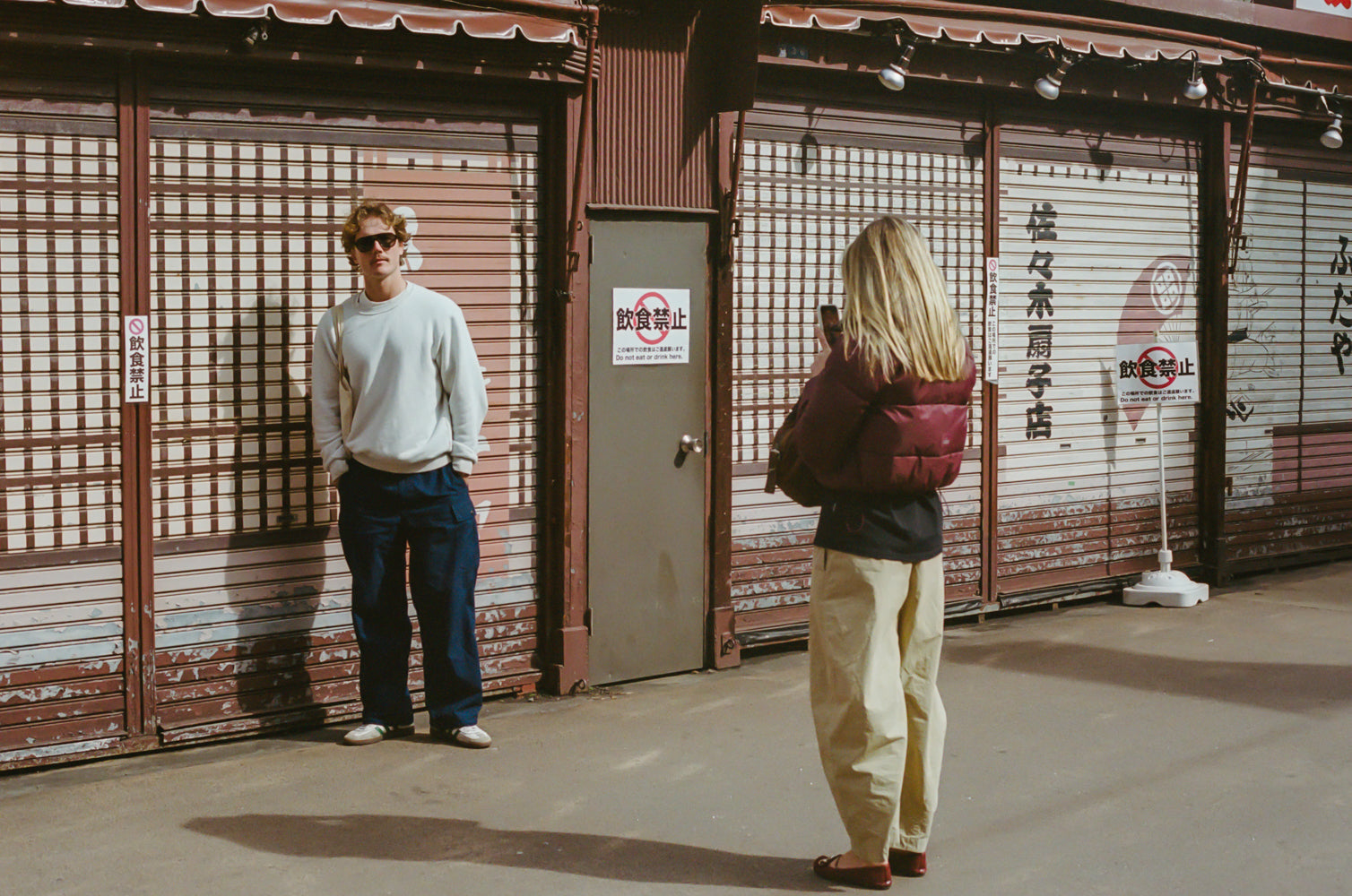 Two people standing in front of a traditional Japanese building with closed shutters.