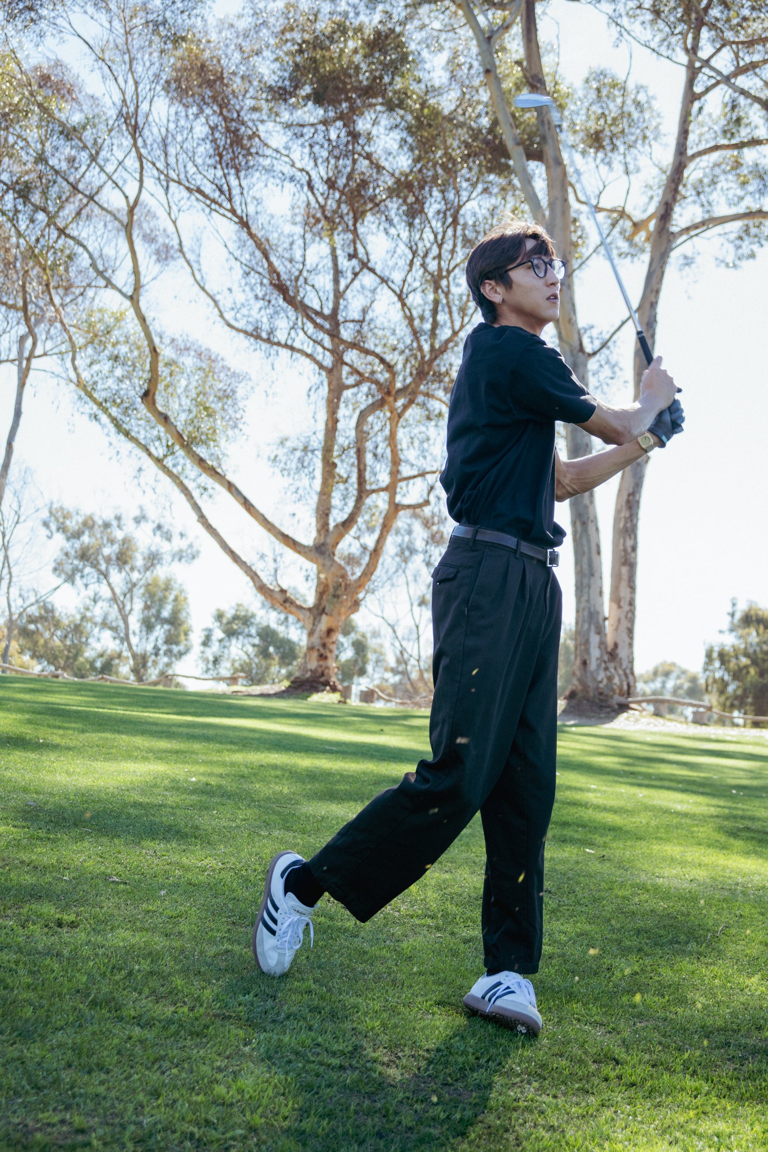Person playing golf on a grassy course with trees in the background