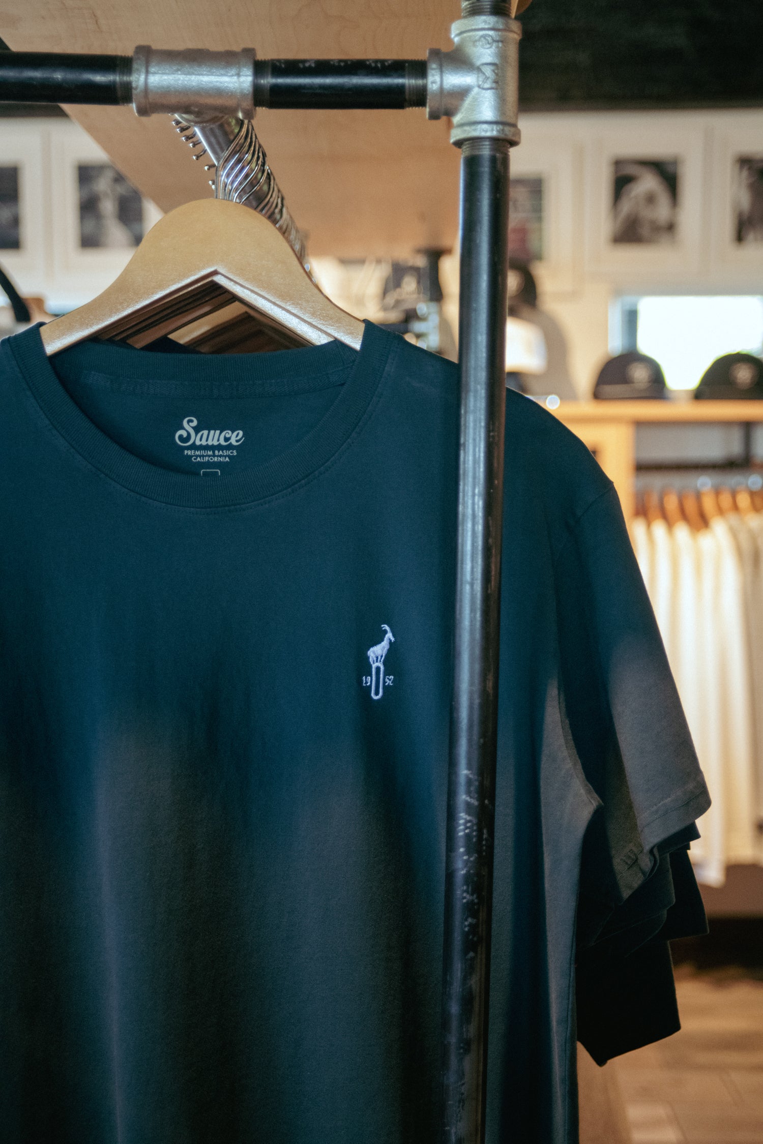 Green t-shirt with a small logo on a hanger in a clothing store.