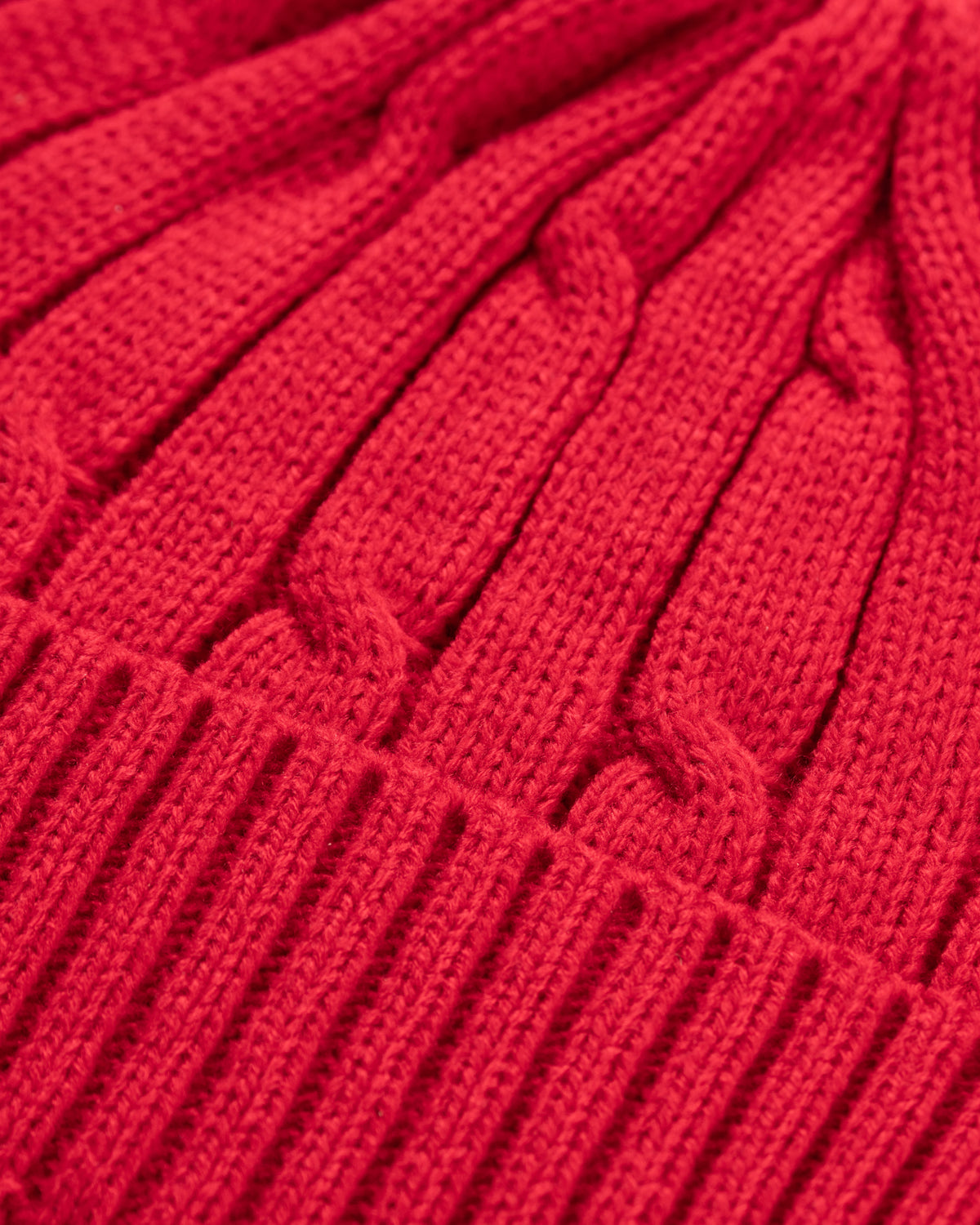 Close-up of a red knitted fabric with cable pattern