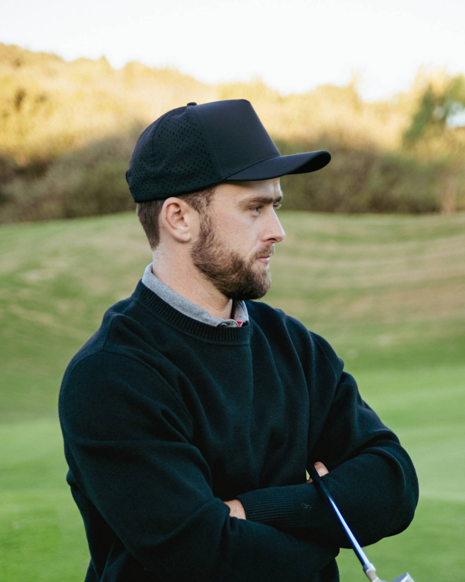 Man wearing hat and sweater on a golf course