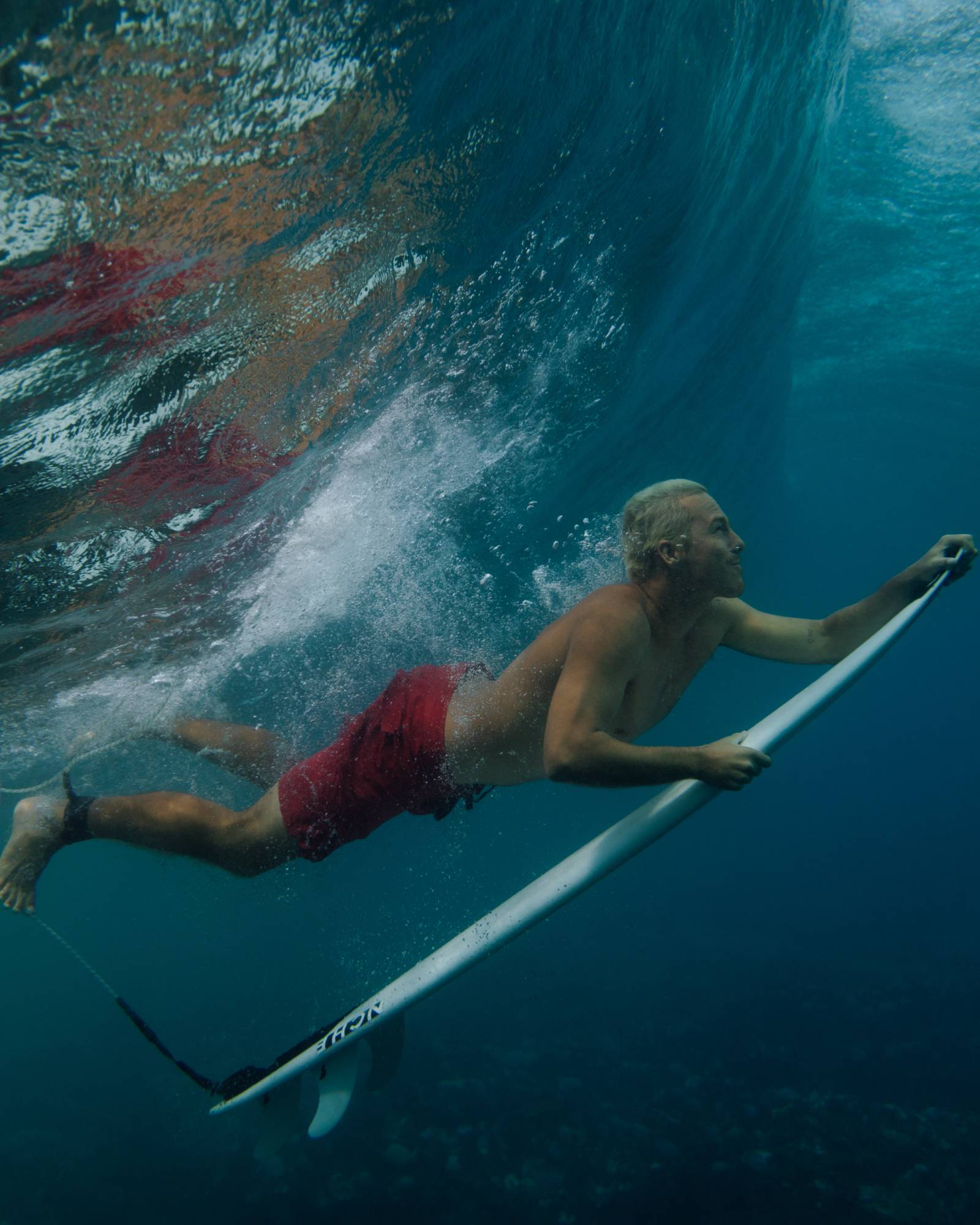 Man duck diving under a wave on a surfboard